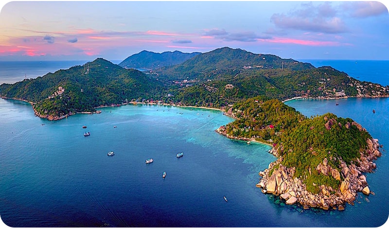 A panoramic view of Koh Tao, Thailand, showcasing its lush green hills, pristine beaches, and turquoise waters. A perfect place to visit in thailand