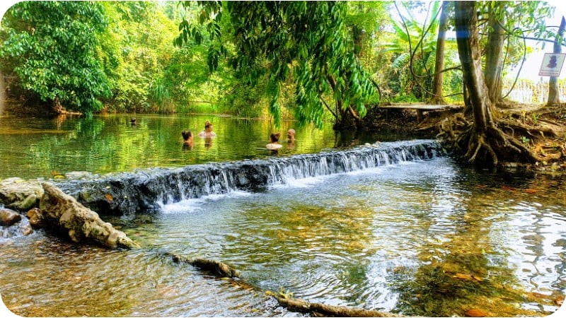 People enjoying the soothing waters of the Pai Hot Springs, a popular tourist destination in Thailand.