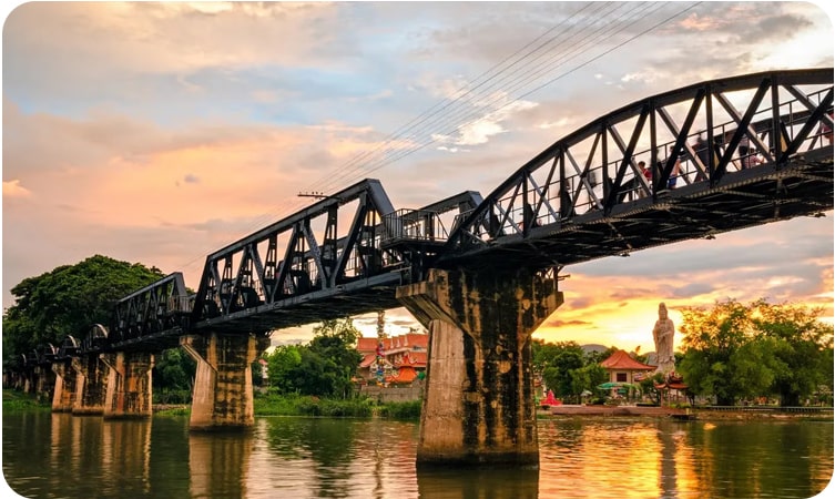 Sunset view of the historic River Kwai Bridge, a popular tourist destination in Thailand.